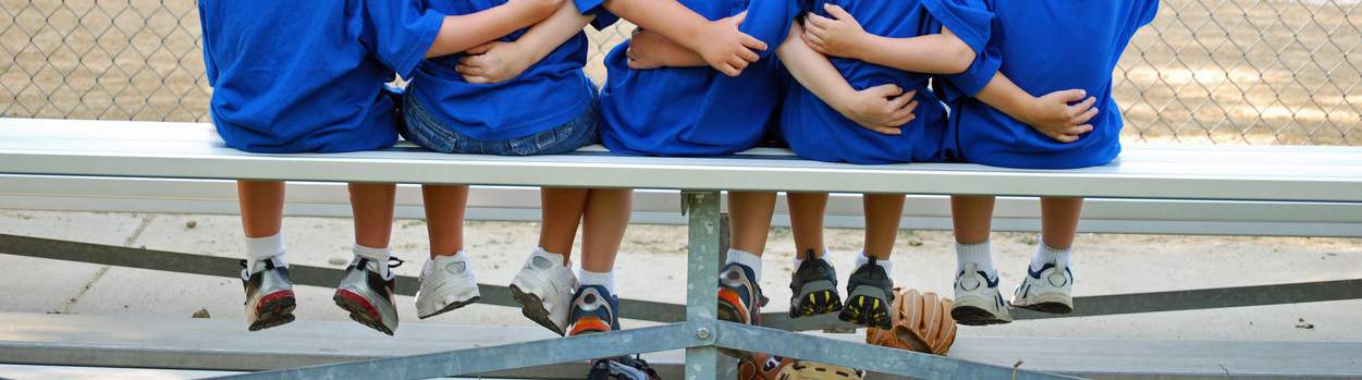 five little boys put their arms around each other before their baseball game
